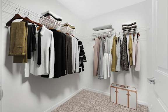 A white closet with clothes hanging on hangers.