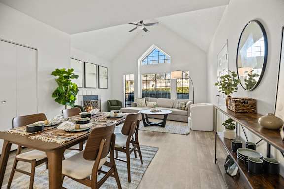 A dining room with a table set for six and a couch in the background.