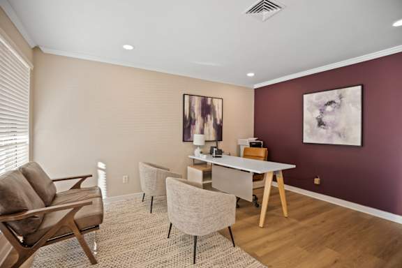 A living room with a brown chair, a grey chair, and a white table.