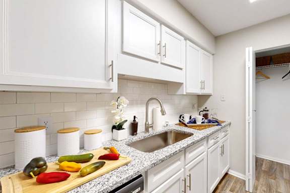 A kitchen with white cabinets and a granite countertop.