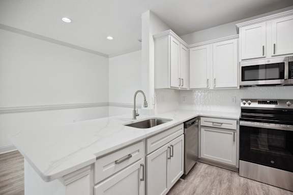 A modern kitchen with white cabinets and stainless steel appliances.