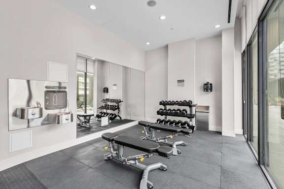 A gym with a mirror, weights, and exercise equipment.