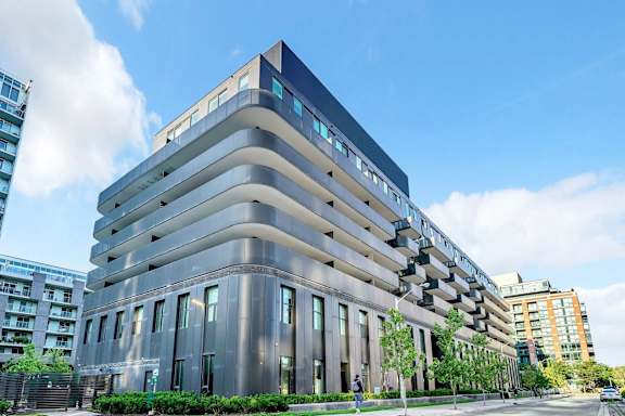 A modern building with a curved design and a blue sky in the background.