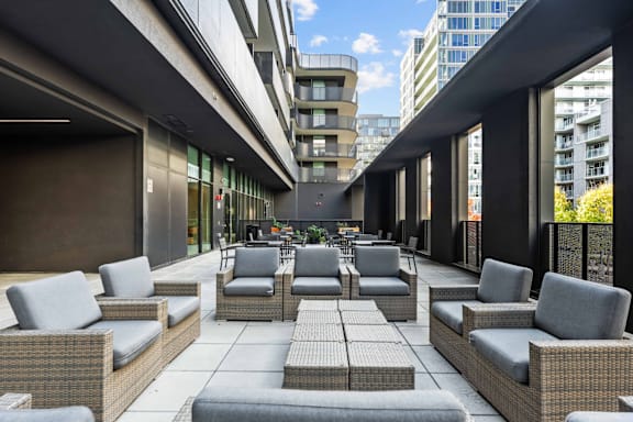 A patio with grey wicker furniture and a black awning.