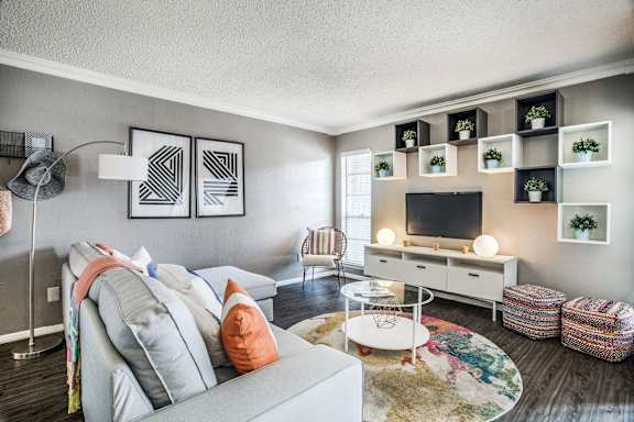 A living room with a grey couch, a white coffee table, and a TV on a white stand.