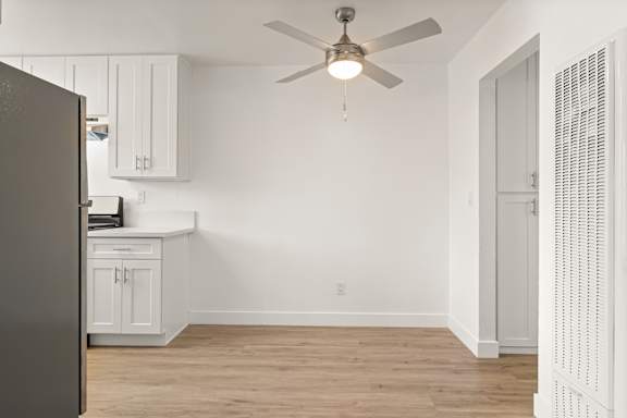 A room with a ceiling fan and a refrigerator.
