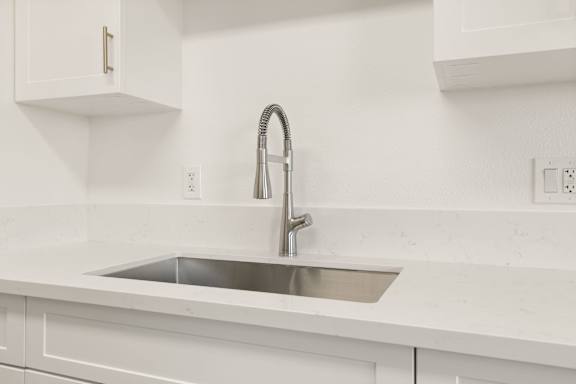 A modern kitchen with a white sink and faucet.