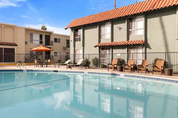 A swimming pool in front of a building with a red tile roof.