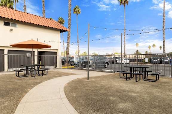 A patio area with picnic tables and a red umbrella.