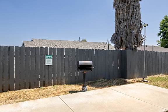 A black mailbox is on the sidewalk in front of a wooden fence.