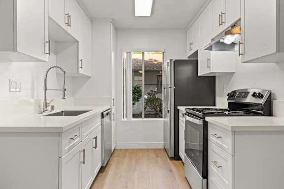 A kitchen with white cabinets and a black refrigerator.