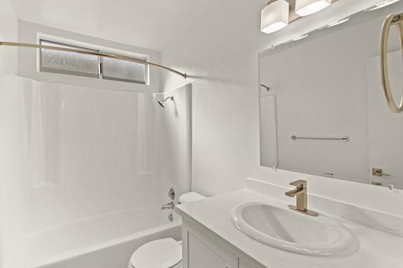 A white bathroom with a toilet, sink, and tub.
