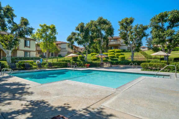 a swimming pool with trees and apartments in the background