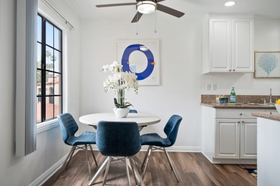 a dining area with a round table and blue chairs and a ceiling fan