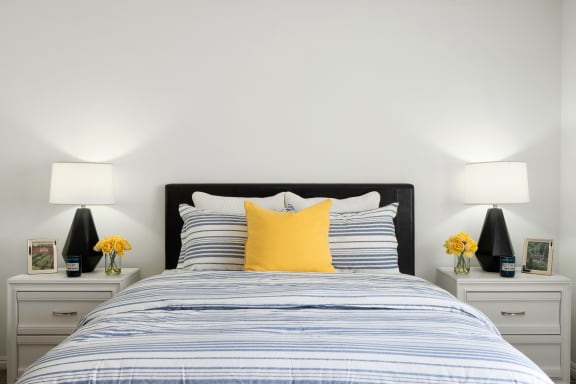 a blue and white bed with yellow pillows in a bedroom