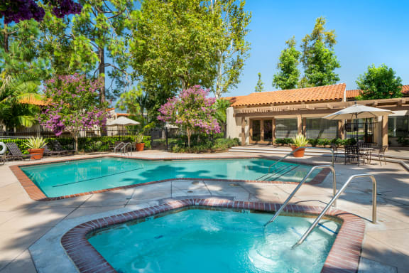 a swimming pool with a hot tub and a resort style building in the background