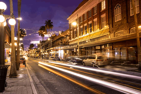a city street at night with cars driving down it