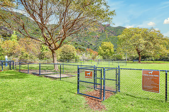 A sign in front of a fence that says "Leashed Dog Park".