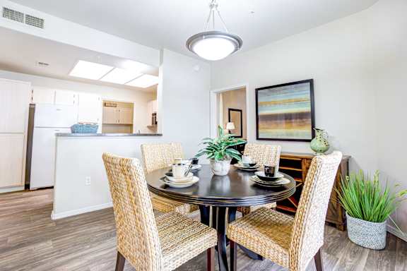 A dining room with a table set for two and a painting on the wall.
