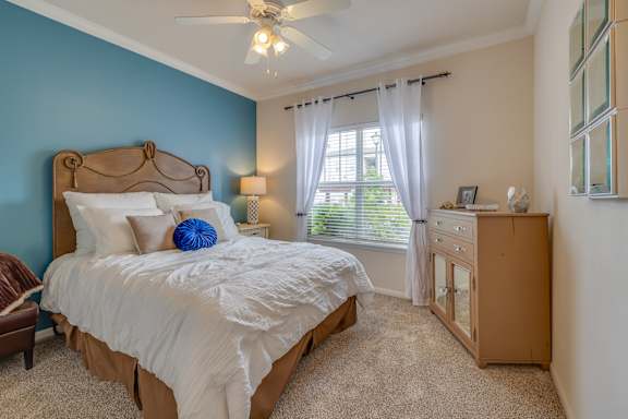 A bedroom with a bed, dresser, and window.
