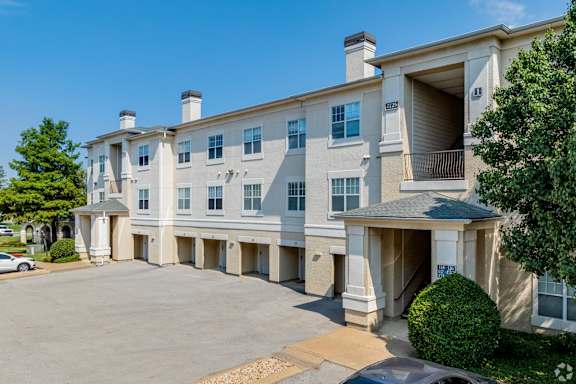 A large, multi-story apartment building with a parking lot in front.