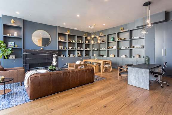 A modern living room with a brown leather couch and a wooden floor.
