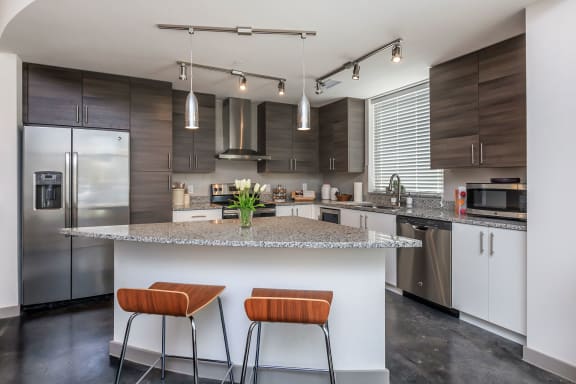 a kitchen with dark wood cabinetry and a large island with a granite countertop and two