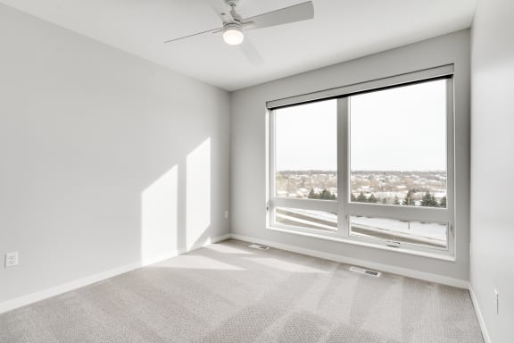 Spacious luxury bedroom with large window and ceiling fan at Aspire at CityPlace in Woodbury, Minnesota