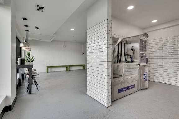 large room with white tiled walls and a stainless steel dog wash