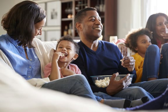 a family sitting on a couch eating popcorn and watching a movie