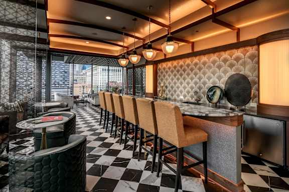 A restaurant with black and white checkered flooring and wooden chairs.