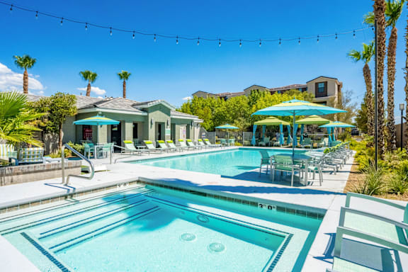 A sunny day at the pool with palm trees and a building in the background.