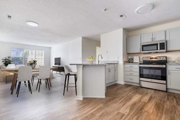 A kitchen with white cabinets and a dining table with chairs.