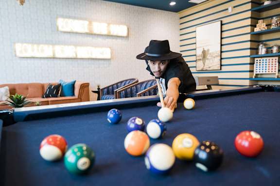 A man in a hat is playing pool.