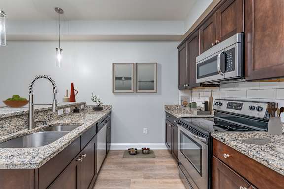 A kitchen with dark wood cabinets and granite countertops.