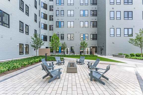A modern courtyard with benches and a tree in front of a building.