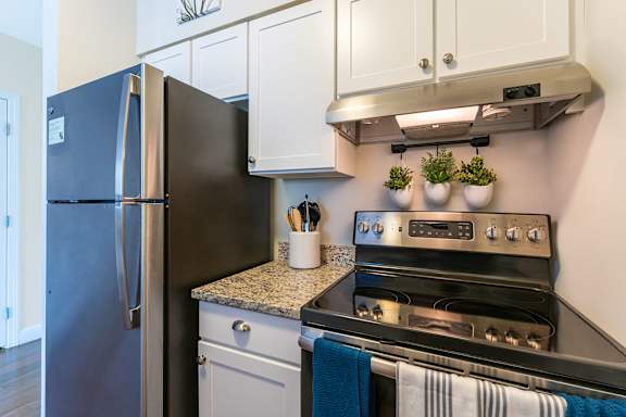 Parkside Commons kitchens with white cabinets, a refrigerator is next to a stove in a kitchen.