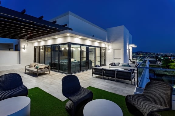 a terrace with chairs and couches at night