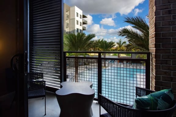 a balcony with a table and two chairs and a pool in the background