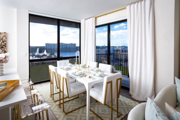 a dining area with a white table and chairs and a large window with a view of a