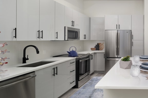 a kitchen with white cabinets and a large white island with a blue rug