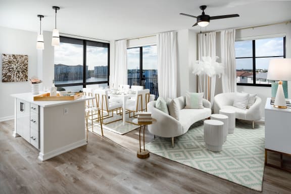 a living room and dining area with white furniture and a green rug