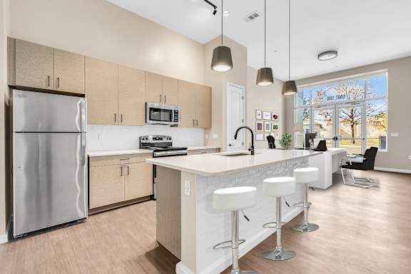 A kitchen with a refrigerator, stove, and bar stools.