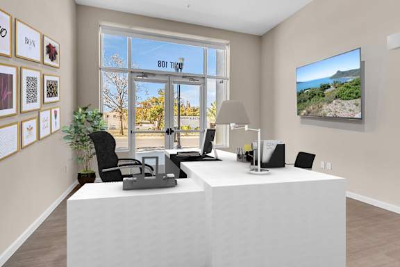 A white reception desk with a laptop and a phone on it.