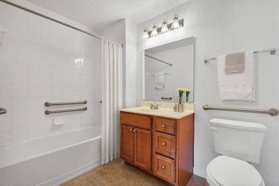 A white toilet sits next to a bathroom sink with a mirror above it.