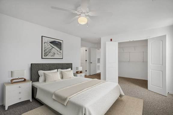 A bedroom with a large bed, a ceiling fan, and a picture on the wall.