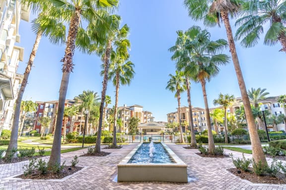 a fountain surrounded by palm trees in the middle of a resort