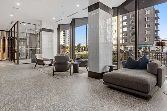 A modern living room with a grey sofa and a glass door.