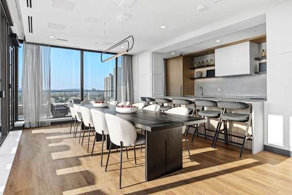 A modern kitchen with a long table and chairs.