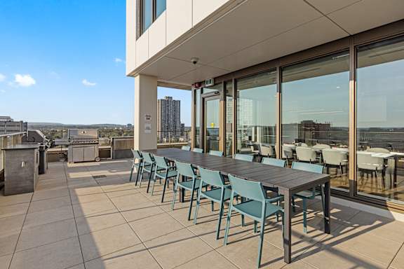 A patio with a table and chairs overlooking a cityscape.